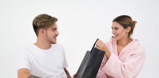 11 College Care Package Ideas for Guys woman holding black paper bag sitting in front of the man