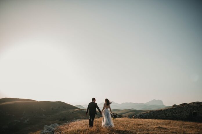 Photo by Foto Pettine a bride and groom walking on a hill